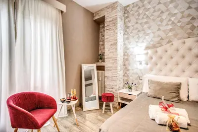 a bedroom with a large bed and a red chair at Santamaria Inn in Rome