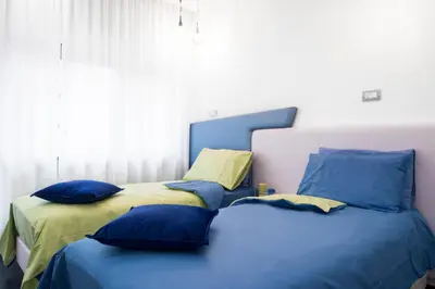 two beds in a bedroom with blue and yellow pillows at Ma Belle Maison in Rome