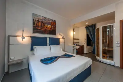 a bedroom with a large white bed with blue accents at Hotel California in Rome