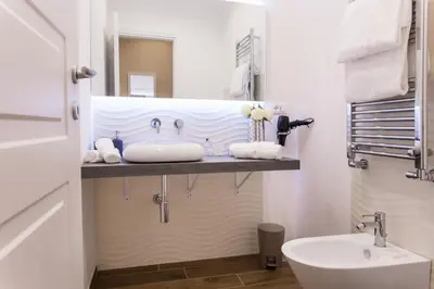 a white bathroom with a sink and a toilet at Nazionale Palace Suites in Rome