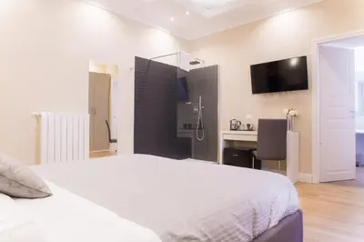 a bedroom with a white bed and a desk at Nazionale Palace Suites in Rome