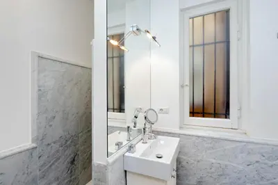 a white bathroom with a sink and a mirror at Prestigious Apartment Via Veneto in Rome
