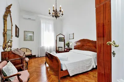 a bedroom with a bed and a chair and a mirror at Prestigious Apartment Via Veneto in Rome