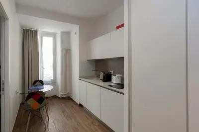 a kitchen with white cabinets and a table and a chair at Vatican Scipioni 113 in Rome