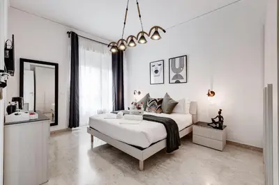 a white bedroom with a large bed and a sink at DIDAVI' Guest House in Rome