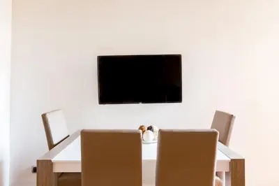 a dining room table and chairs with a television on the wall at The Hide Trastevere in Rome