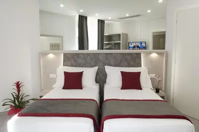 two beds with red pillows in a room at Merulana Holidays in Rome
