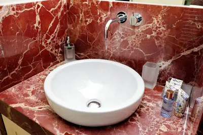 a white sink in a bathroom with a red marble wall at Boccaccio 22 in Rome