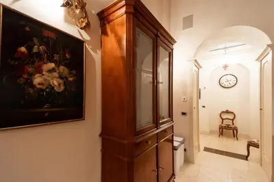 a hallway with a large wooden cabinet with a painting of flowers at Boccaccio 22 in Rome