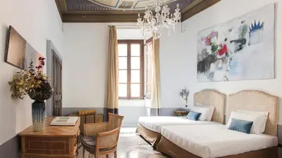two beds in a room with a table and chairs at Nobildonne Relais in Rome