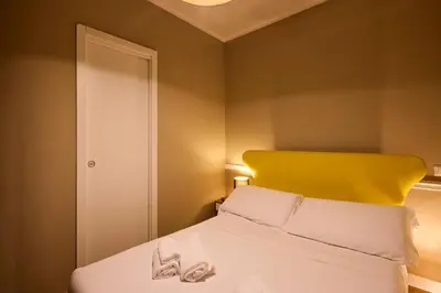 a bedroom with a white bed with a yellow headboard at DEM Hotel in Rome