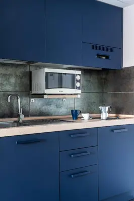 a kitchen with blue cabinets and a microwave at Patrizia Romana Palace in Rome