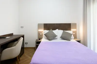 a bedroom with a large bed with a desk and a bed sidx sidx at Hotel Casa Tra Noi in Rome