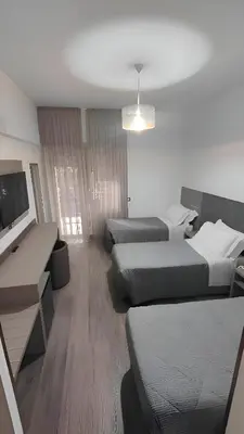 a hotel room with two beds and a desk at Hotel Casa Tra Noi in Rome