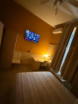 a room with a tv on the wall and a bed at Guest House Hola Roma in Rome