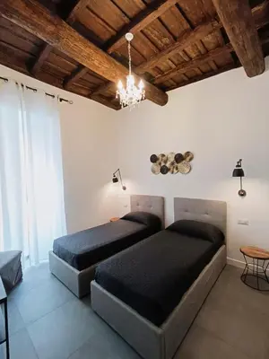 two beds in a bedroom with a chandelier at La tua casa a ViadelCorso in Rome