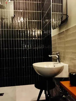 a bathroom with a sink and a black tiled wall at Tiburtina Suites, Roma in Rome
