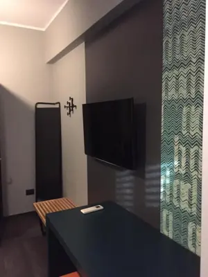 a room with a table and a tv and a cross on the wall at Tiburtina Suites, Roma in Rome