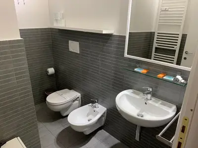 a bathroom with a sink and a toilet and a mirror at Tiburtina Suites, Roma in Rome