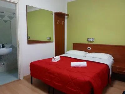 a bedroom with a bed with a red blanket and a sink at La Casa Dell'Arte in Rome