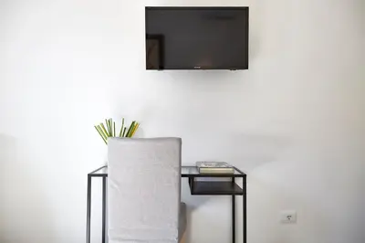 a table with a chair and a tv on a wall at Raffaela's Suite & Rooms Vatican Guest House in Rome