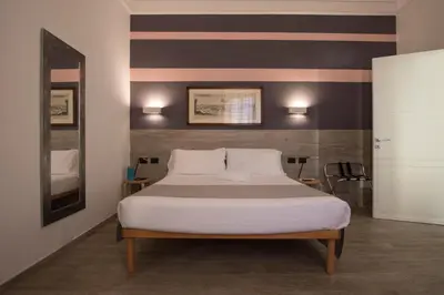 a bedroom with a bed with a striped wall at Raffaela's Suite & Rooms Vatican Guest House in Rome