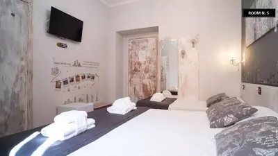 a bedroom with two beds and a tv on the wall at Domus Ferruccio in Rome