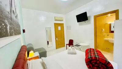 a white room with a bed and a red chair at I Dormienti in Rome