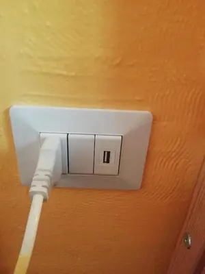 a white outlet with a white cable plugged into it at Casa di Marco a Trastevere in Rome