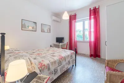 a bedroom with a bed and a window with red curtains at Red & White Vatican Apartment in Rome