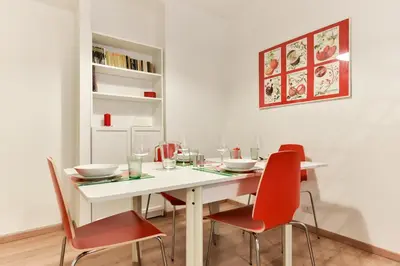 a dining room with a white table and red chairs at Red & White Vatican Apartment in Rome