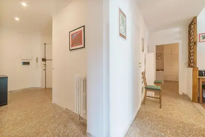 a room with a white wall and a chair at Red & White Vatican Apartment in Rome