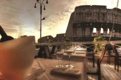 a table with wine glasses on a balcony with the coliseum at Royal House in Rome