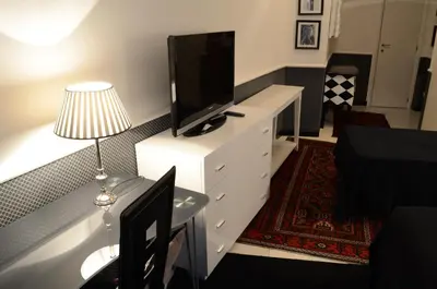 a living room with a television on a white dresser at Sweetdreams Inn in Rome
