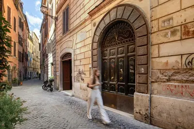 a woman walking down a street in front of a building at The right place 4U Grotte Apartment in Rome