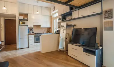 a kitchen with white cabinets and a flat screen tv at Terrace99 in Rome
