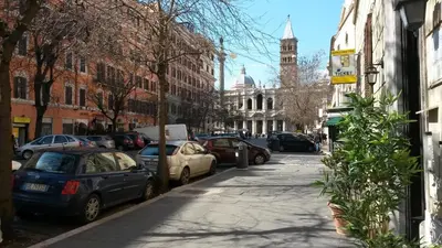 a city street with parked cars and a clock tower at Rome To Stay in Rome