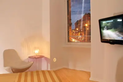 a living room with a white chair and a television at St. Peter Guest House in Rome