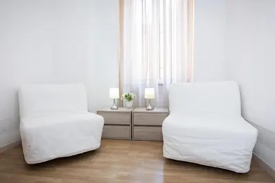 two beds in a room with white walls and wood floors at El Dorado Vatican in Rome