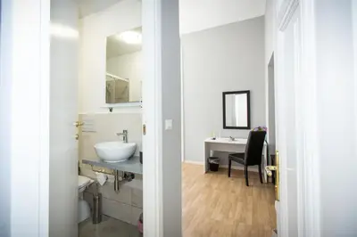 a white bathroom with a sink and a desk at El Dorado Vatican in Rome