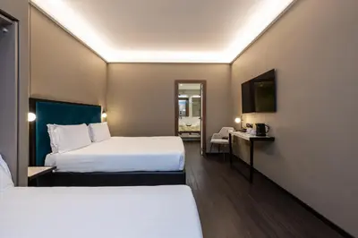 a hotel room with two beds and a chair at Trevi Collection Hotel - Gruppo Trevi Hotels in Rome