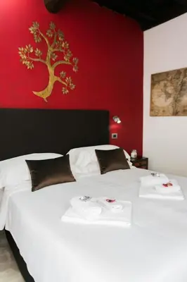 a bedroom with a white bed with a red wall at Navona First Rooms in Rome