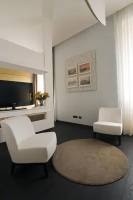 a living room with two white chairs and a television at HT Romeo Al Babuino in Rome