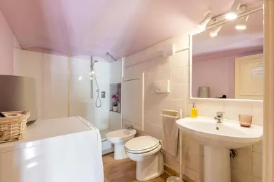 a white bathroom with a toilet and a sink at Colosseum romantic loft in Rome