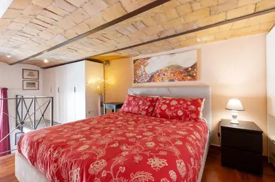 a bedroom with a red bed and a painting on the wall at Colosseum romantic loft in Rome