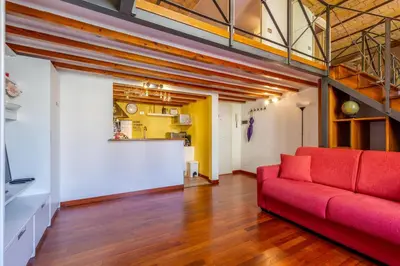 a living room with a red couch and a kitchen at Colosseum romantic loft in Rome