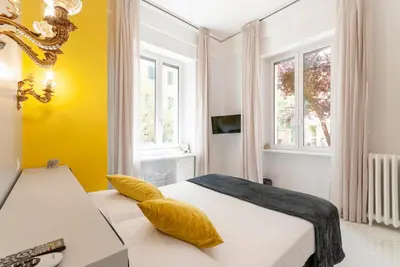 a bedroom with a bed with yellow walls and windows at Bea Suites Luxury Rooms in Rome