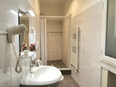 a white bathroom with a sink and a shower at Roman Holidays Rooms Otranto in Rome
