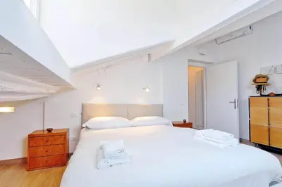 a white bedroom with a large white bed and a dresser at Pantheon Charming Attic | Romeloft in Rome