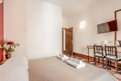 a white room with a bed and a tv on the wall at Ariana Luxury Guest House in Rome